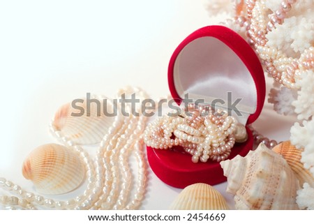 shells, corals and heart-shaped red box with shiny pearl necklace. With copy space on white background.