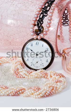 luxury pearl necklaces in the rose crystal vase and antique watch. With a copy space. Focal point is on the watch