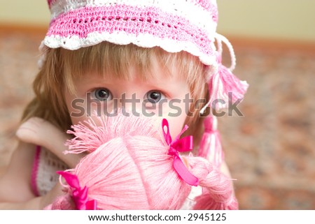 cute little girl with doll in her hands looking into the camera