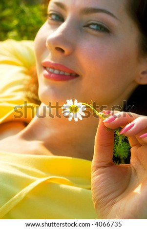 beautiful girl with chamomile lying in the rays of sun. Soft-focused, focal point is on flower