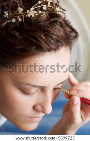 beautician preparing young bride for the wedding and doing make-up. Low DOF, focal point is on eyes