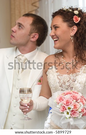 just married - young couple in wedding wear with bouquet of roses and glass of wine