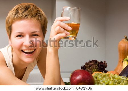 Beautiful woman with glass of juice and fresh fruits in the kitchen