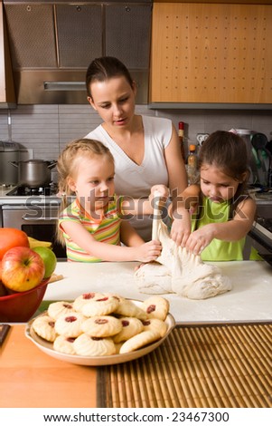 Mother teaching two little girls how to cook