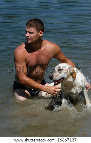 Attractive male with his labrador retriever dog in water