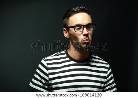 portrait of  macho man in glasses and pursing his lips black background
