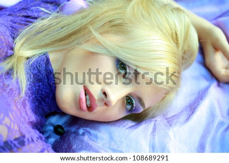 portrait of a pretty young woman with perfect make up and laying on fabric pieces