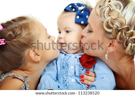 Mother, big sister and little sister kissing on a white background.