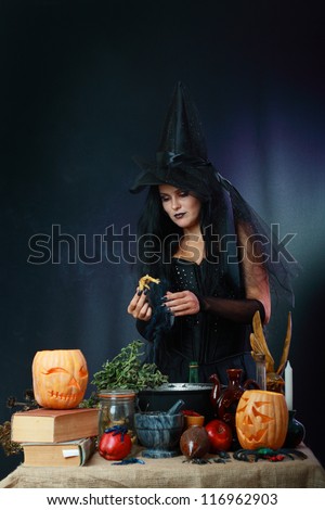Sexy witch on a dark background making potion on wizard kitchen