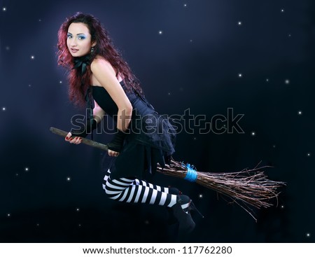 Sexy brunette witch flying on broom on a dark sky with stars