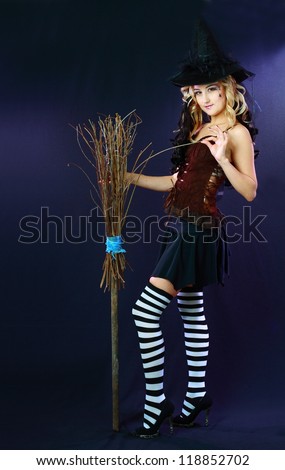 Sexy beautiful witch with broom on dark background