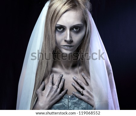 Portrait of beautiful zombie corpse bride looked scary and standing at dark background. shot in studio