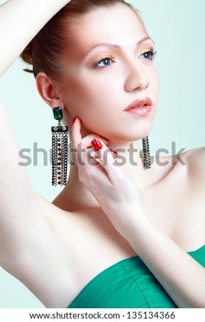 Portrait of beautiful woman with beautiful make-up and hairstyle. Elegant woman with green jewelry