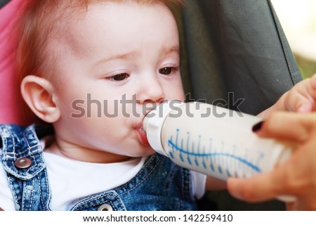 child eating out of a plastic bottle outdoor