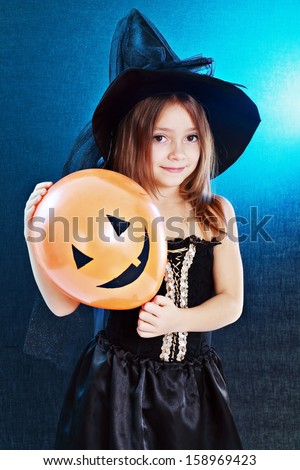beautiful cute little girl in witch halloween costume hold the broom over dark background