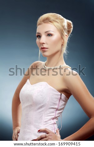 Beautiful adult blond skinny woman posing to camera over dark background