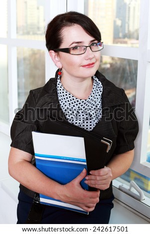 Portrait of a middle age business woman holding folder with files in her arms and looking at you with hope. Isolated on white background