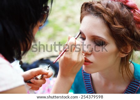 Make-up artist outdoor applying lip liner on model\'s lips, close-up
