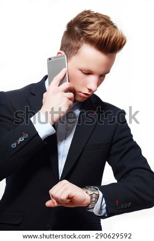 yougn businessman is looking at his watch while taking a call.