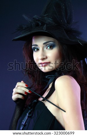Cheerful witch in purple and black gothic fantasy Halloween costume, studio shot on black background