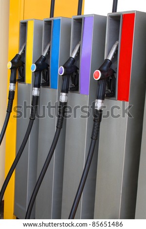 Gas nozzles at the gas station A row of 4 different gas pumps yellow, blue, purple and red