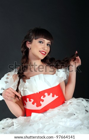 Attractive brunette woman with red lips smiling and playing with her braids in white and red paper dress