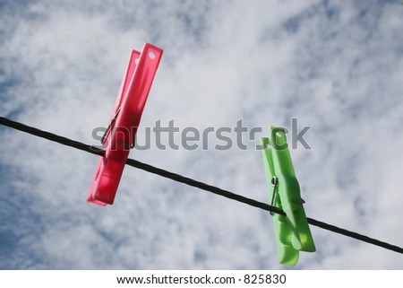 Two plastic pegs on clothes line with clouds overhead