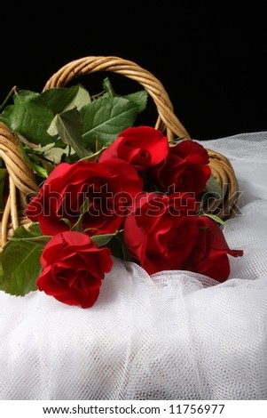 long stem red roses in wicker basket on white tulle net fabric