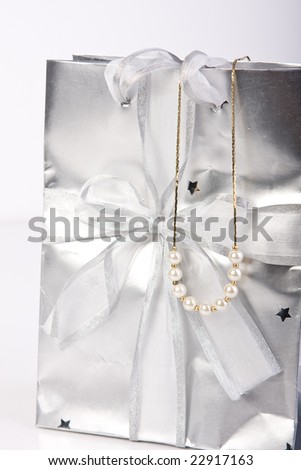 close up of decorative silver gift bag with ribbon and pearl jewelry