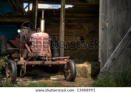 The Old Farm Tractor. An old 40\'s era farm tractor sitting in the doorway of it\'s barn. This is a high dynamic range image.