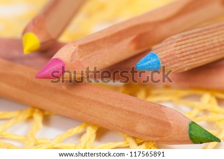 A couple of colored Pencils in Blue Red, Yellow and green on a yellow table pad