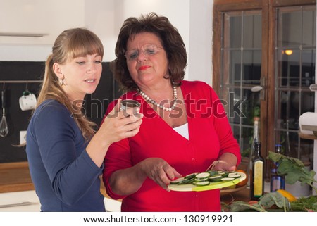 A older and a younger women are cooking in a kitchen and having fun