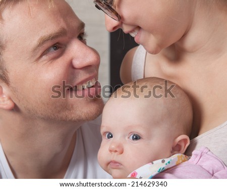 A young couple is very happy about there baby.Baby is looking interested in