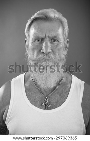 Front portrait of a cool looking  senior man with a white beard and cool look. Man is wearing a white t-shirt.