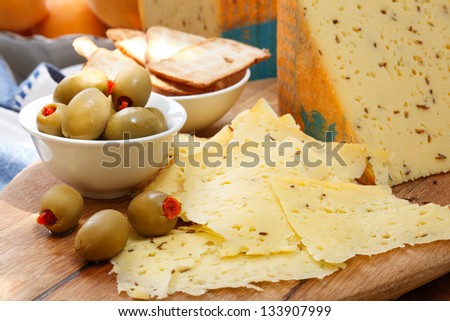 mouthwatering shaved cheese biscuit and peppadew stuffed green olives on a wooden platter