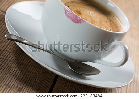 Image of a cup of coffee with a red lipstick stain from a woman drinking