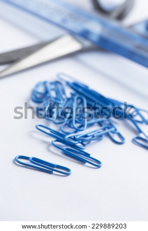 Multicoloured paper clips scattered on a white surface