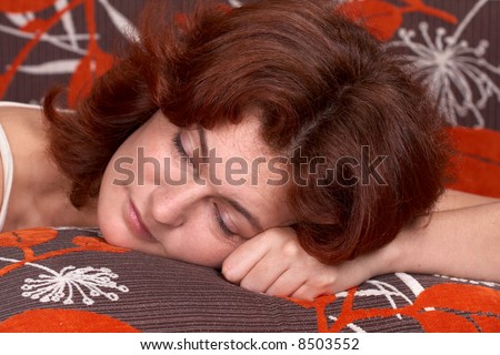 A beautiful red-haired woman taking a nap on her bed.