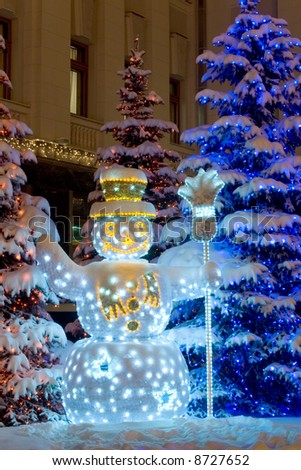 snow man under fir tree decorated with garland