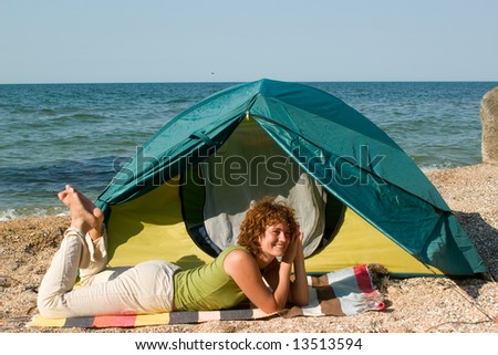 Smniling girl lie near of her tent at seaside