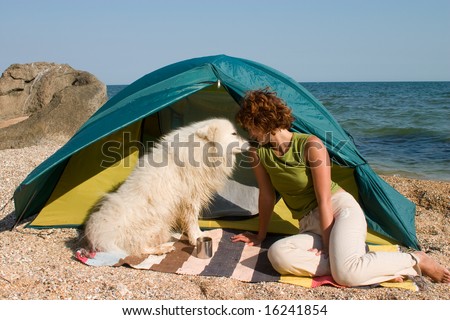 Girl with dog sitting near of a tent at seaside