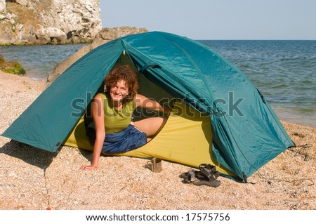 Smiling girl looking from a tent at seaside