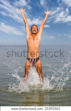Happy man jump in sea with splashes