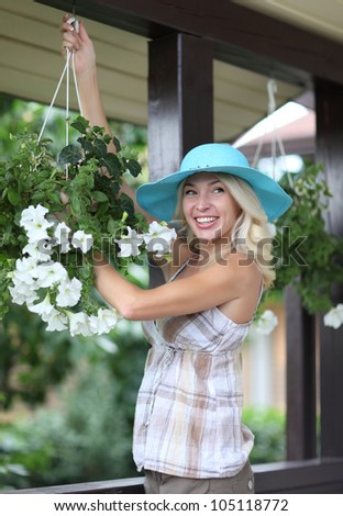 Young woman holding a hanging flower basket and smiling
