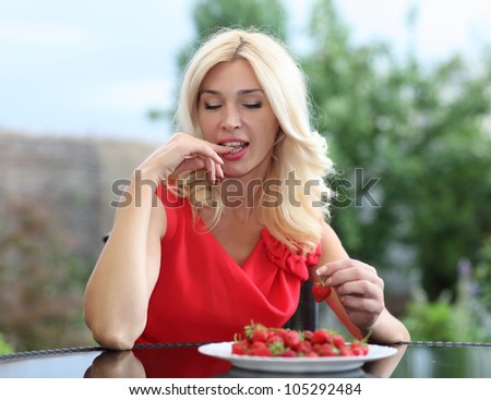 Blonde beautiful girl laughing eating and playing with fresh strawberry