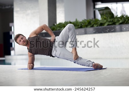 fitness, sport, training, gym and lifestyle concept. 	Man at the gym doing stretching exercises and smiling on the floor