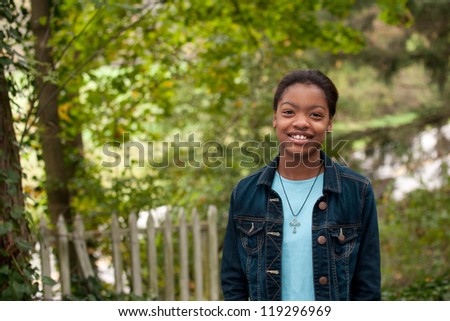 An African-American girl standing in front of an old fence in the country