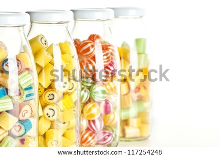 close up of four jars containing various hard candy, focus on a jar with smiley face candy