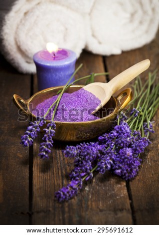 Lavender bath salt in brass bowl, fresh flowers, scented candle and towels