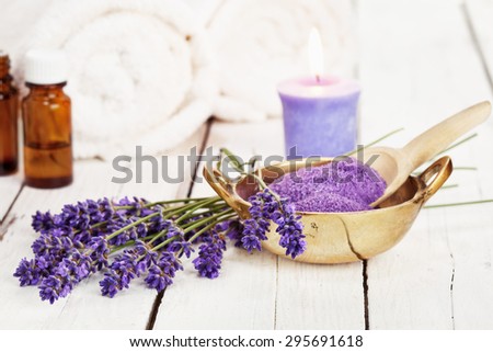 lavender flowers, bath salt, massage oil, scented candle and towels on rustic white background, high key image